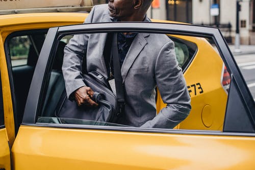 裁剪黑人男子坐在出租车停在街上 · 免费素材图片
