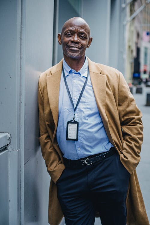 微笑与徽章在城市街道上的自信黑人经理 · 免费素材图片