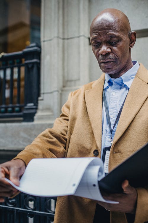 体贴的非洲裔美国人，阅读街上的文件 · 免费素材图片