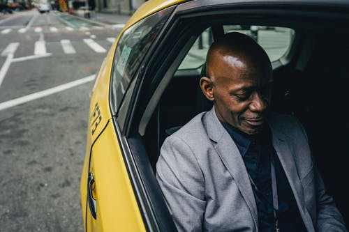 积极的黑人男子，穿着正式的西装，乘坐出租车 · 免费素材图片