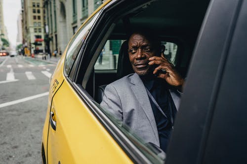 周到的黑人男子乘坐出租车和通电话 · 免费素材图片