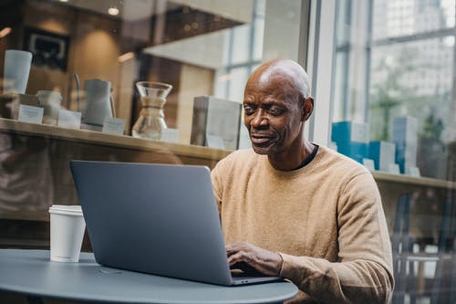 冷静在咖啡馆外的笔记本电脑的黑人商人 · 免费素材图片