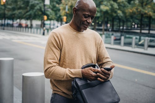 黑人在路附近浏览智能手机 · 免费素材图片