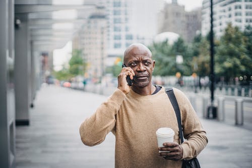 严重的黑人男性，在大街上有电话 · 免费素材图片