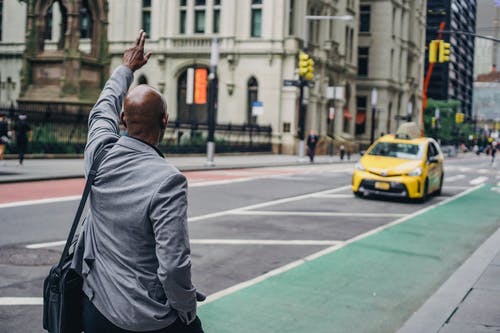 黑人男子在西装赶上明亮的黄色出租车 · 免费素材图片