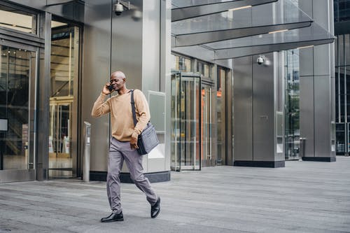 优雅的黑人企业家，在电话上走路和说话 · 免费素材图片
