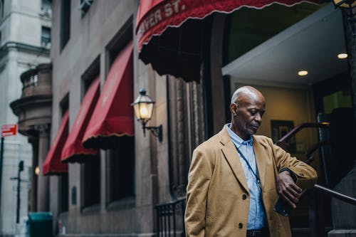 时尚的黑人男子，站在大街上，检查时间 · 免费素材图片