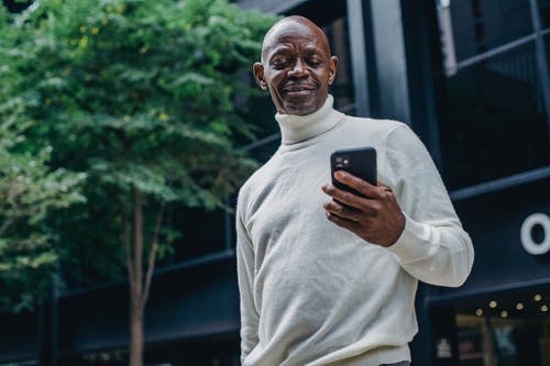 性格开朗的黑人男子，在大街上浏览智能手机 · 免费素材图片