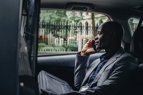 沉思的黑人男子，坐在车里谈到智能手机 · 免费素材图片