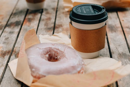 美味的甜甜圈和外卖咖啡放在木质的表面 · 免费素材图片