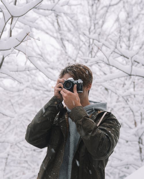 男摄影师在冬季树林里拍照 · 免费素材图片