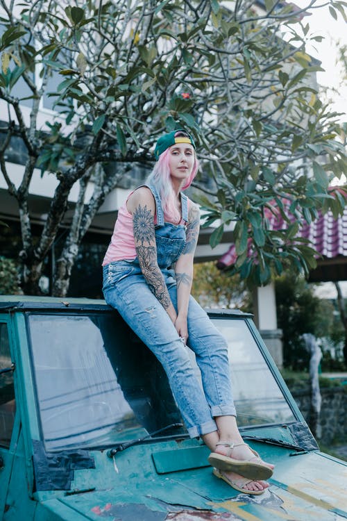 粉红色的头发，坐在老年的汽车屋顶上的年轻女子 · 免费素材图片