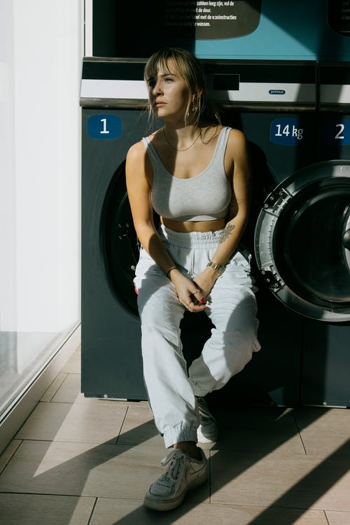 靠在洗衣机上的年轻女子 · 免费素材图片