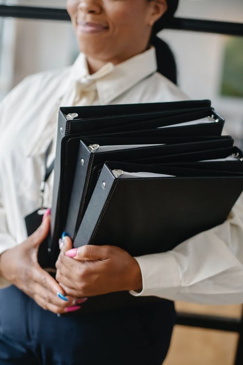 黑人妇女携带堆文件在办公室 · 免费素材图片