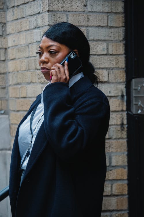 自信的年轻黑人女性员工谈在大街上的智能手机 · 免费素材图片