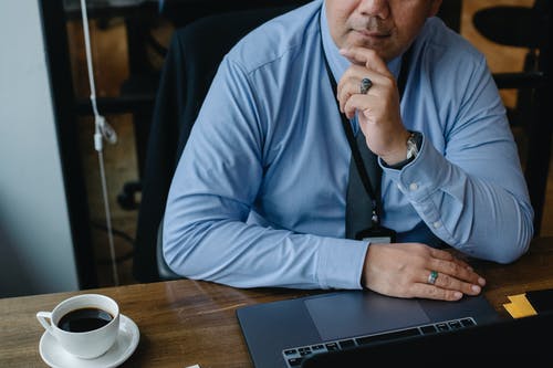 在笔记本电脑上工作时的严肃的商人抚摸下巴 · 免费素材图片