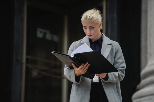 集中办公大楼外的女商人阅读报告 · 免费素材图片