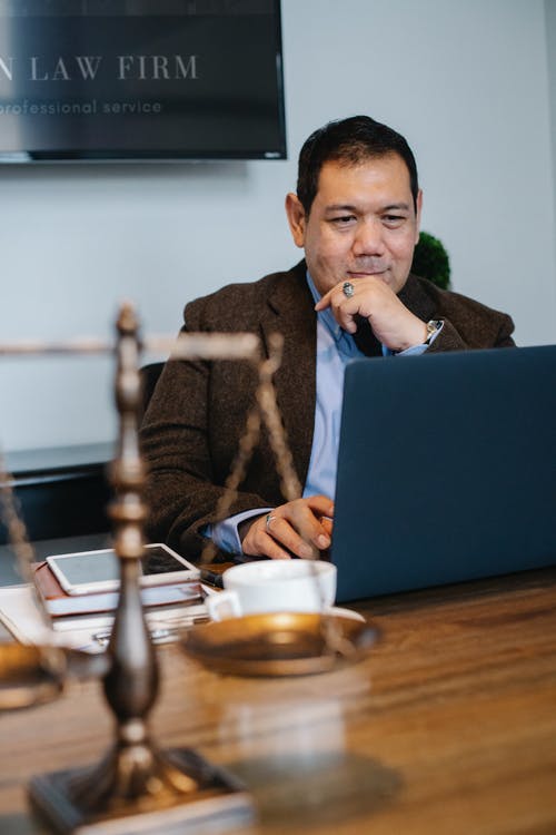 看在桌上的愉快的亚裔律师膝上型计算机与片剂 · 免费素材图片