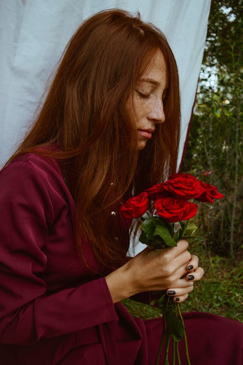 休息在有玫瑰花束的公园的时兴的年轻红头发人夫人 · 免费素材图片