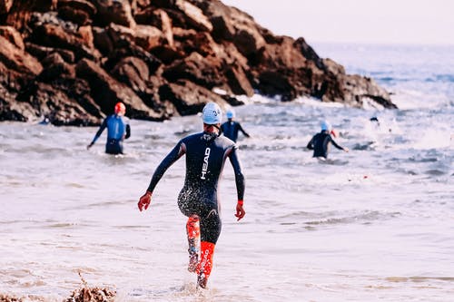 不可识别的运动员，穿着潜水衣在泡沫的海洋里游泳 · 免费素材图片