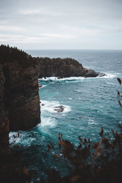 在波涛汹涌的大海，阴云密布的天空的岩石峭壁 · 免费素材图片