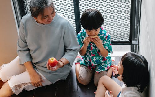 可爱的民族兄弟姐妹和祖母在家里吃水果 · 免费素材图片