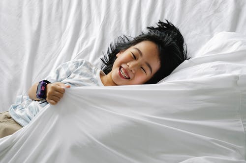 说谎在床上的愉快的亚裔小女孩 · 免费素材图片