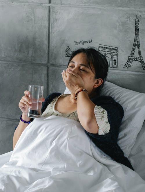 不健康的族裔女人躺在床上休息时吃药 · 免费素材图片
