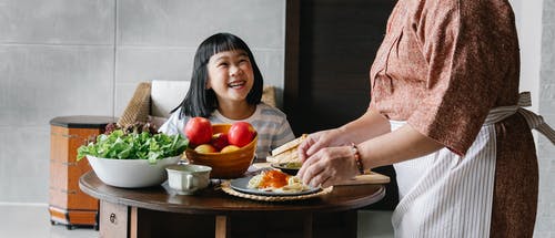 快乐的亚洲女孩和奶奶聚集在餐桌旁吃午饭 · 免费素材图片