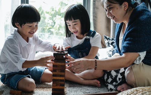 小可爱的亚洲兄弟姐妹和微笑的祖母一起玩塔游戏 · 免费素材图片