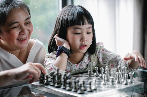 可爱的族裔孩子和祖母下棋时做动作 · 免费素材图片