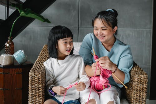 美满的亚洲孩子与祖母坐在扶手椅上和编织 · 免费素材图片