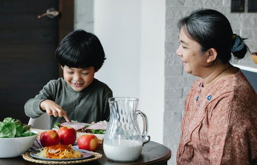 快乐的亚洲祖母和孙子在厨房里吃午饭 · 免费素材图片
