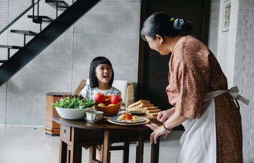 快乐的民族老妇为可爱的孙女服务健康的午餐 · 免费素材图片