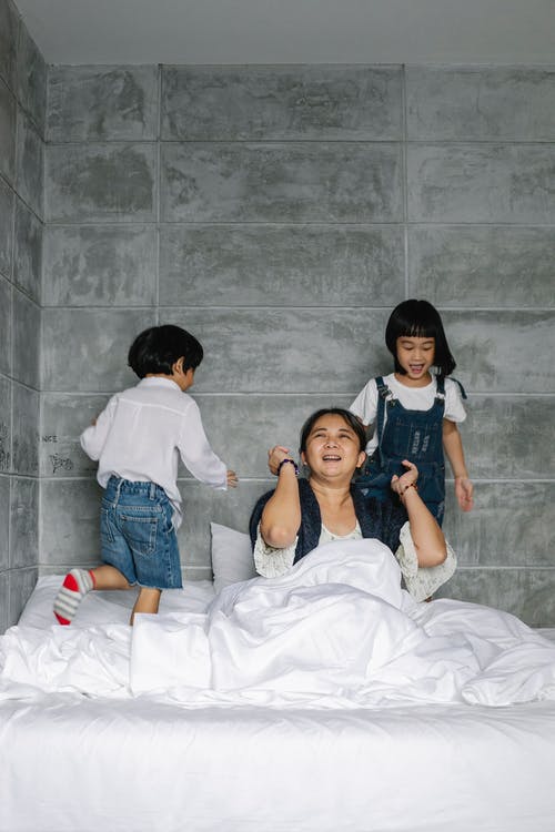 可爱的亚洲孩子打扰快乐祖母在早上坐在床上 · 免费素材图片