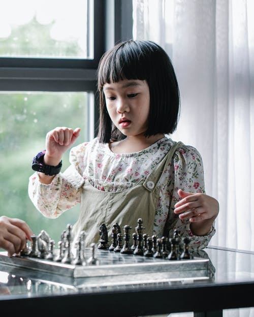 集中亚洲女孩在明亮的房间里下棋 · 免费素材图片