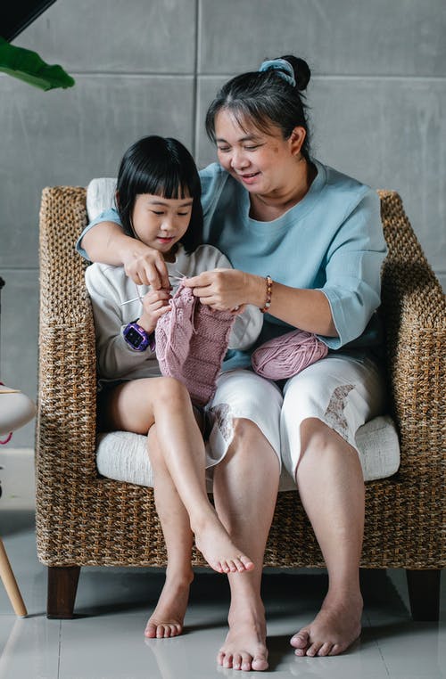 快乐的亚洲孩子和善良的祖母编织保暖的衣服 · 免费素材图片
