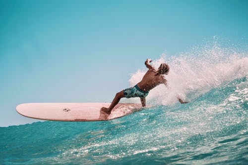 运动型赤膊家伙在海洋中的冲浪板上保持平衡 · 免费素材图片