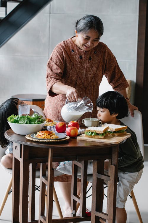 亚洲奶奶倒杯牛奶给孙子 · 免费素材图片