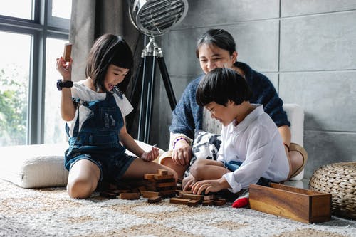 快乐的族裔孩子与祖母在地板上玩塔游戏 · 免费素材图片