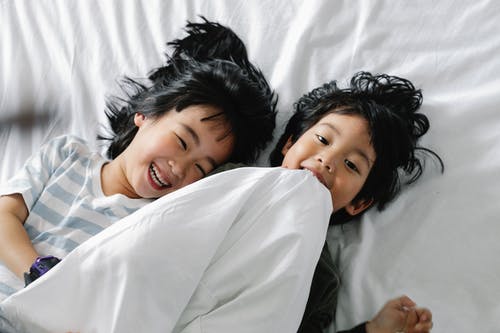 孩子们躺在白色的床上 · 免费素材图片