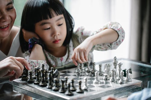 沉思的亚洲女孩下棋 · 免费素材图片