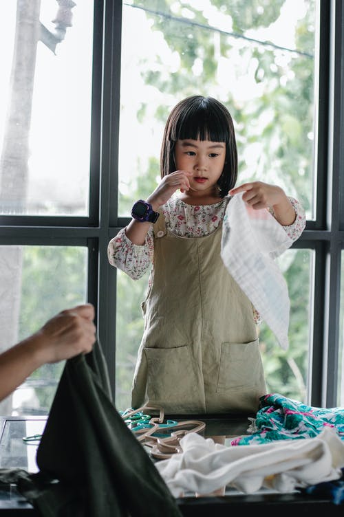 选择衣裳的正面亚裔女孩堆积在桌上 · 免费素材图片