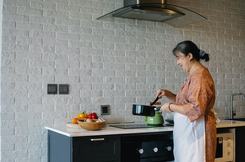 在现代的厨房里做饭的亚裔女子 · 免费素材图片