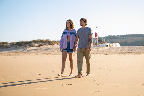 男人和女人在海滩上行走 · 免费素材图片