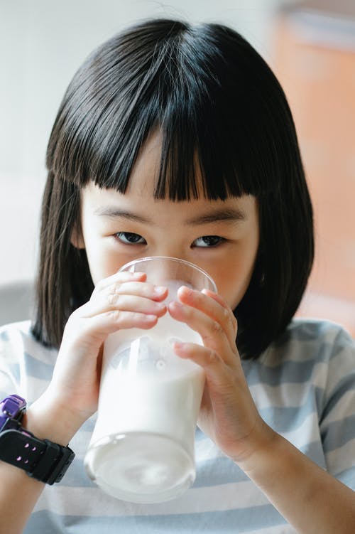 可爱的亚洲女孩从玻璃喝牛奶 · 免费素材图片