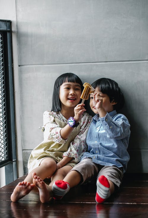可爱的亚洲孩子叮当响的冰淇淋，坐在地板上 · 免费素材图片