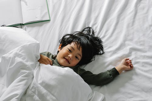 种族男孩睡后躺在床上 · 免费素材图片