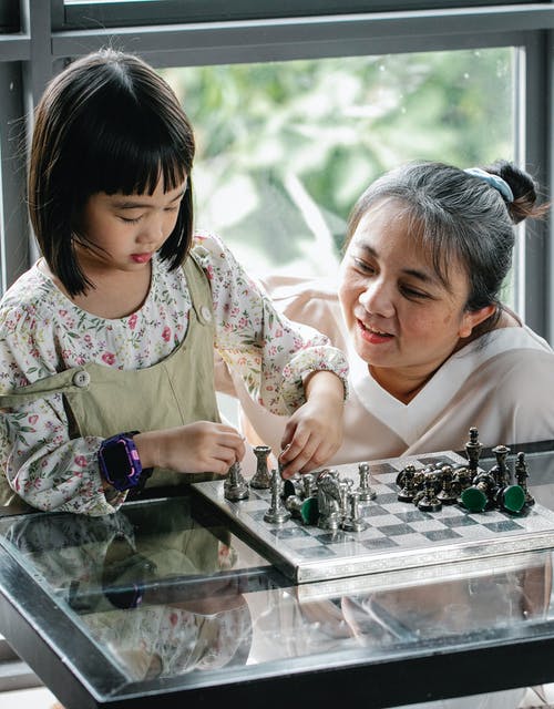 聚焦与祖母下棋的亚洲女孩 · 免费素材图片