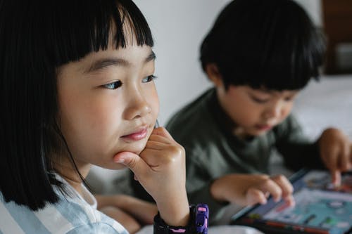 亚洲体贴的小女孩和哥哥使用平板电脑 · 免费素材图片
